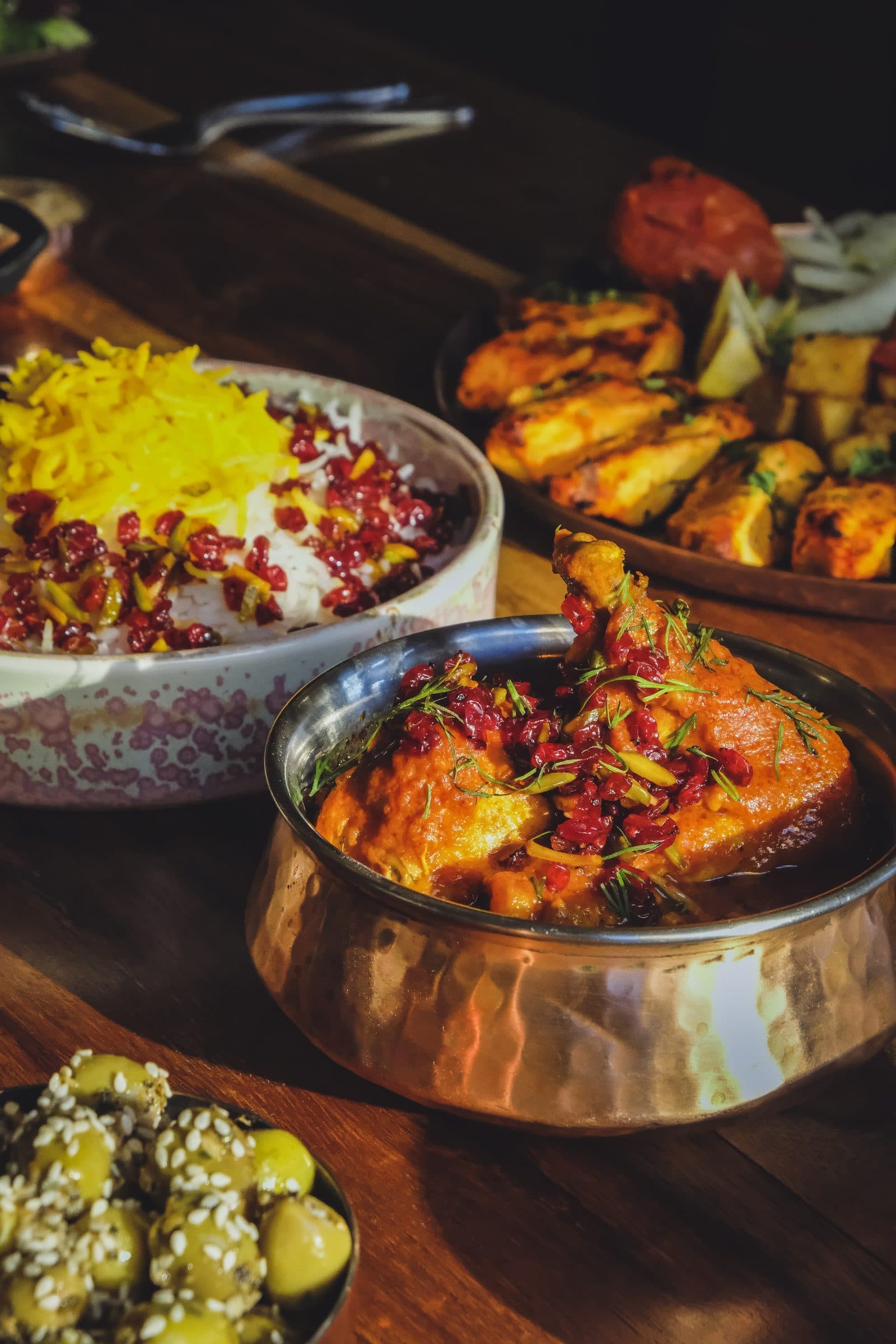 Charcoal-grilled koubideh kebabs and jewelled saffron rice with grilled tomato, laid on a wooden board
