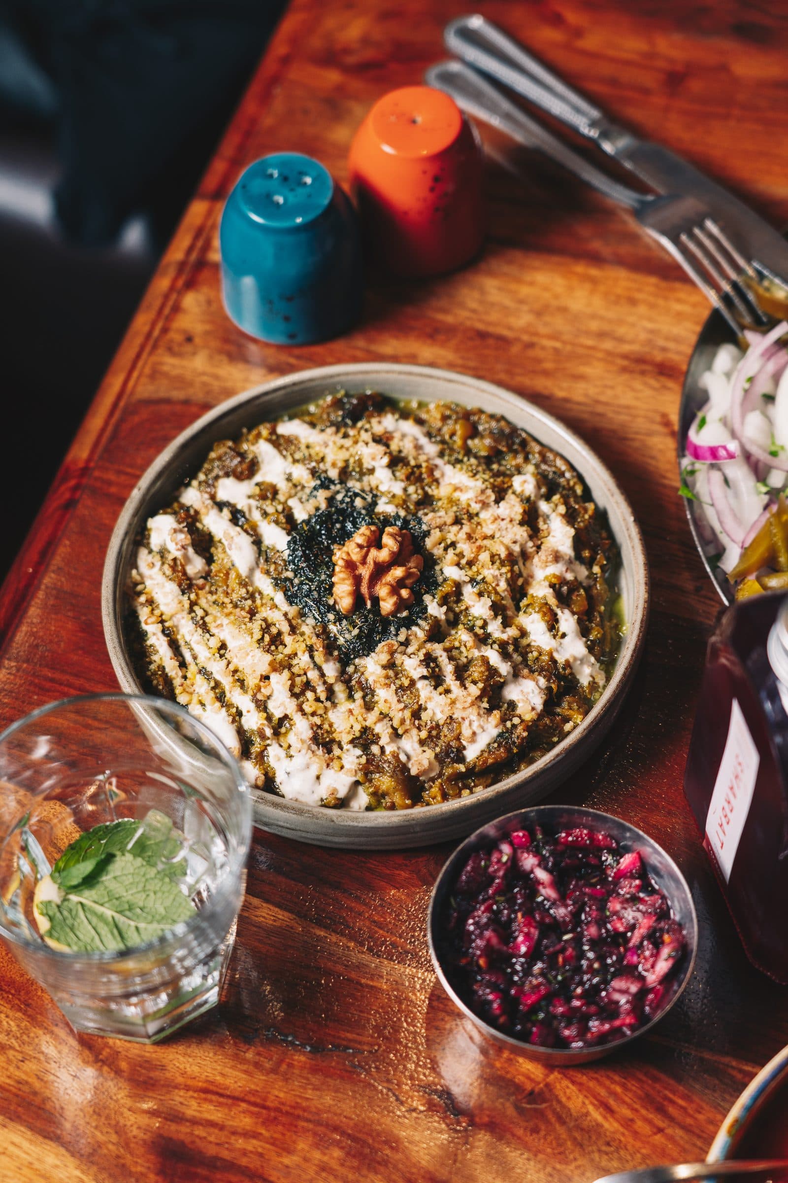 A candlelit mazzeh spread to share — a walnut-topped dip and beetroot bourani on dark wood